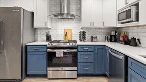 A modern kitchen with white cabinets, a stainless steel refrigerator, a built-in oven, and a microwave.