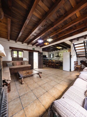 Un intérieur rustique avec des poutres apparentes, un canapé, une table basse et un coin cuisine.