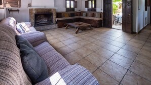 Uma sala ampla com um teto de madeira grande, uma lareira de pedra e um sofá com almofadas.