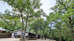 A cabin with a deck, surrounded by trees. - Rustic Bungalow - Rugged with a Touch of Class (Sulphur)