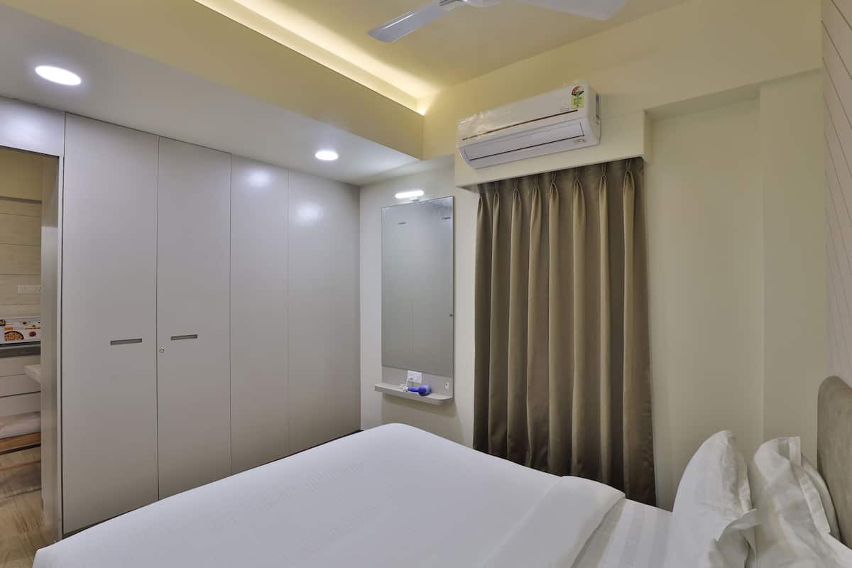 Una habitación de hotel con cama, armario, espejo, aire acondicionado y ventilador de techo.
