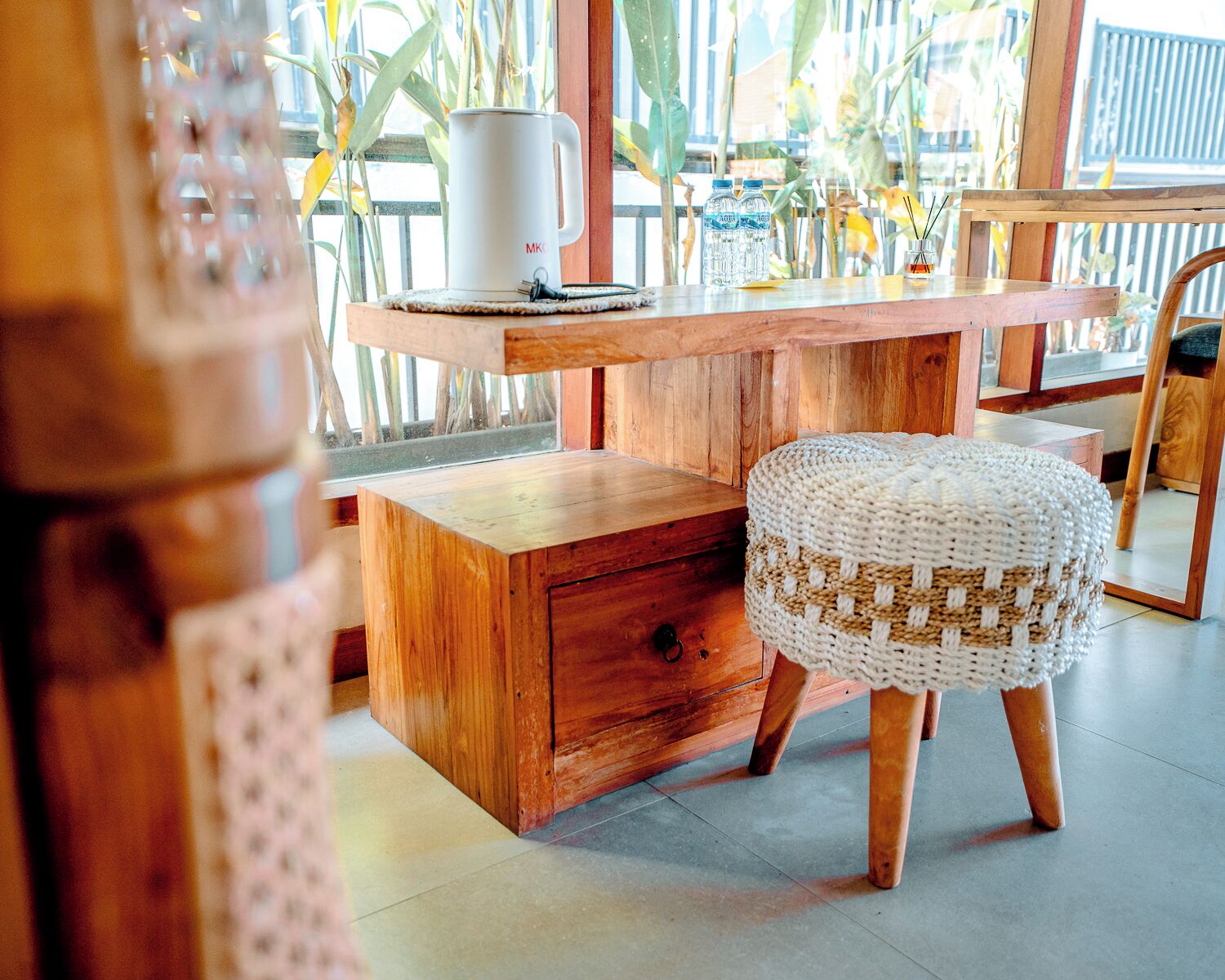 A wooden desk with a mug, water bottles, and a candle holder.