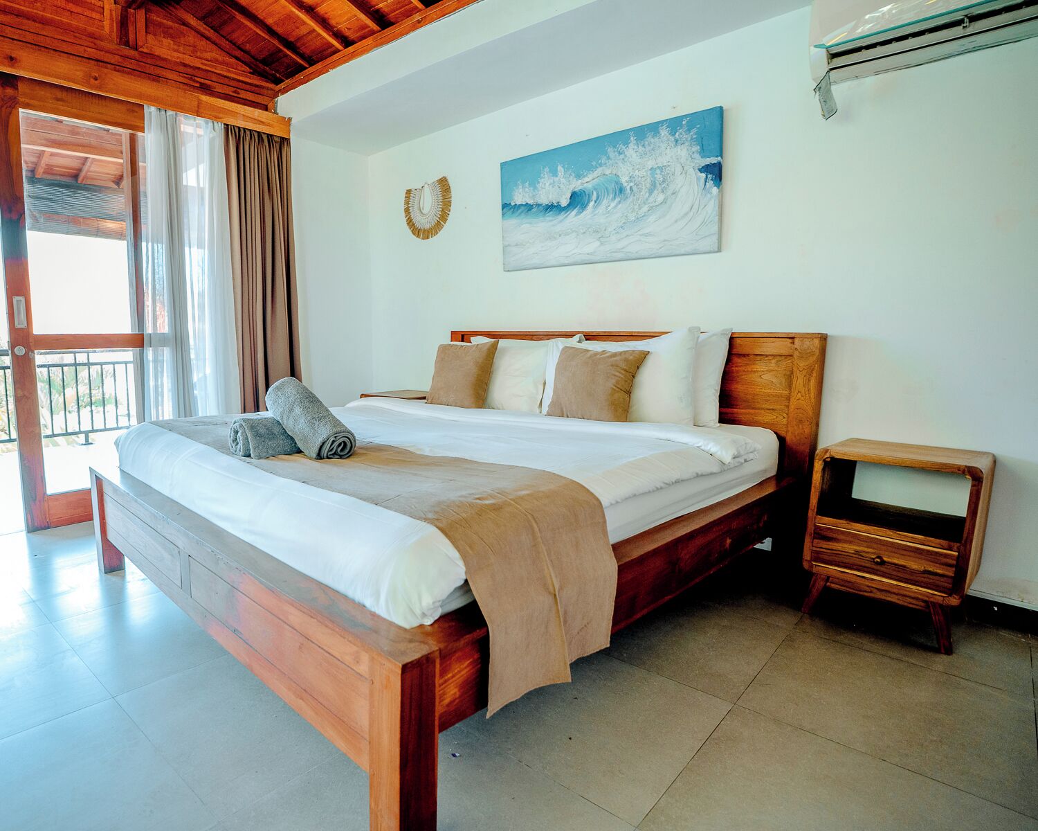 Quarto com cama de madeira, mesa de cabeceira, um quadro na parede e vista pela janela.