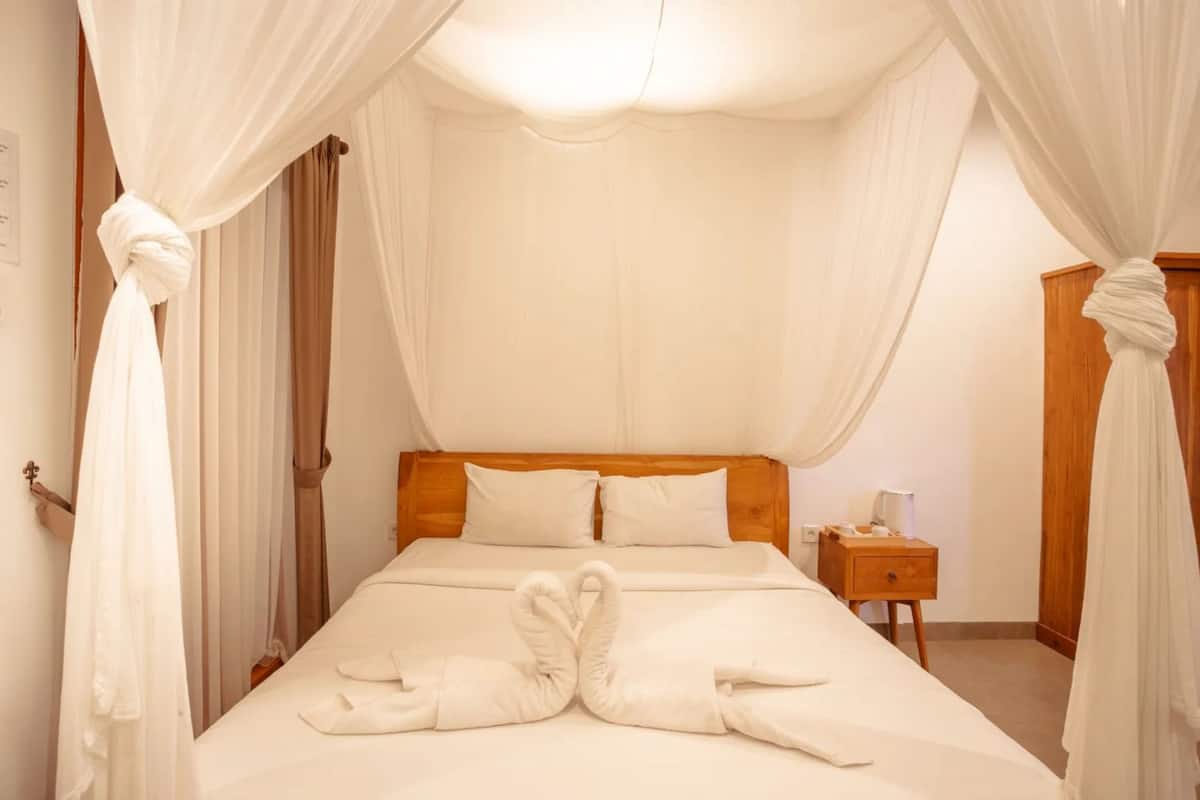 Un lit à baldaquin, une table de chevet avec une lampe et une porte avec un rideau.