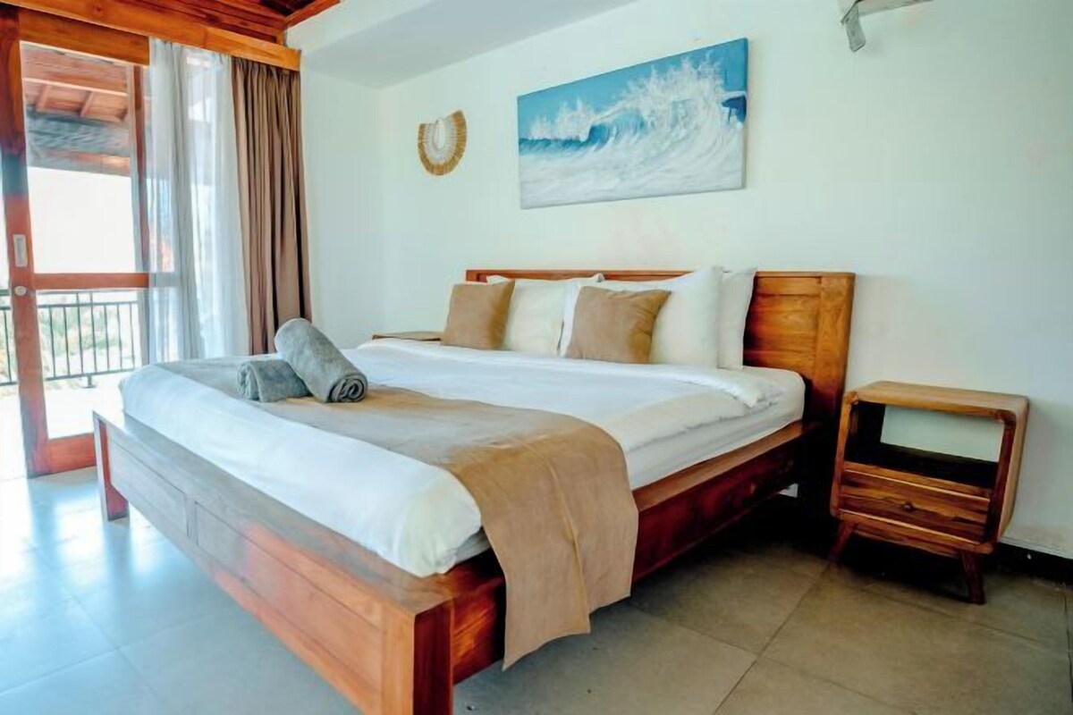 A bedroom with a wooden bed, a nightstand, and a painting on the wall.