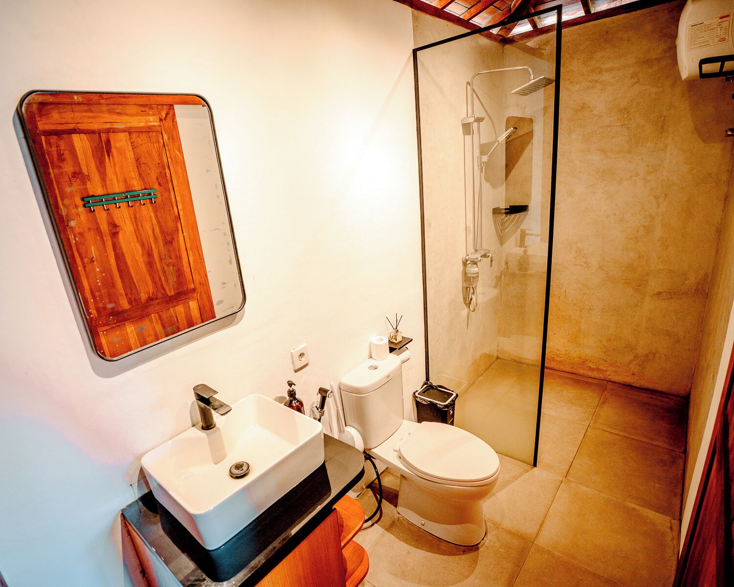 A bathroom with a wooden vanity, a white sink, a toilet, and a glass-enclosed shower.
