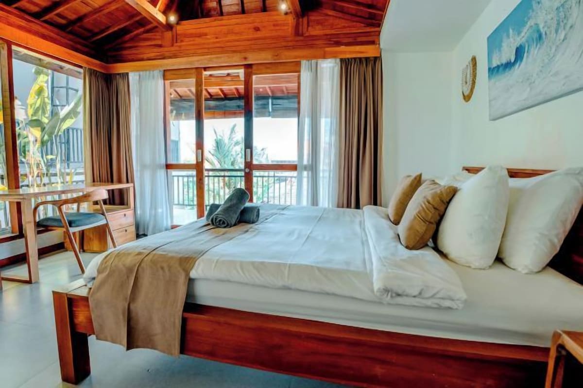 Une chambre à coucher avec un lit, un bureau et une vue sur l’extérieur.
