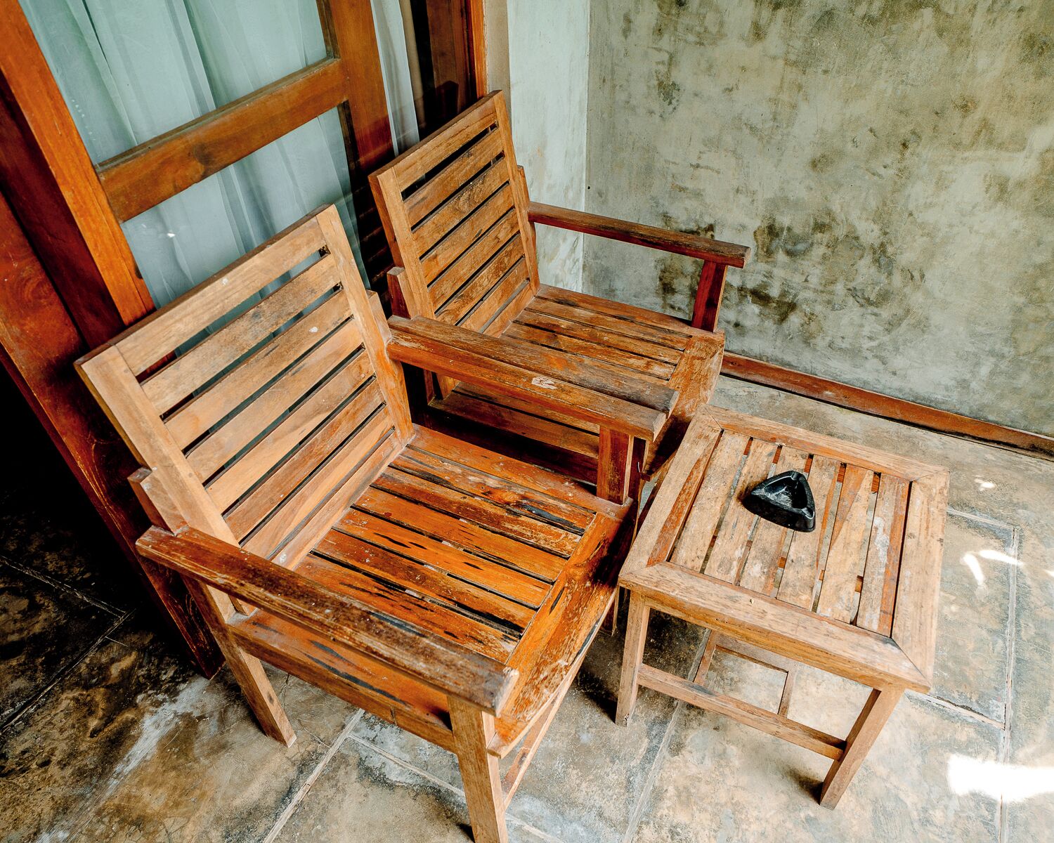 A wooden chair and a small table with a black object on it.