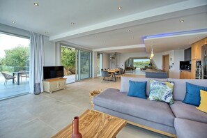 Relax in this open-plan living space with a comfortable sofa, dining area, and kitchen, perfect for meals and socializing.
