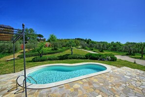 Relax by the clear pool surrounded by a beautifully maintained garden and paved path.