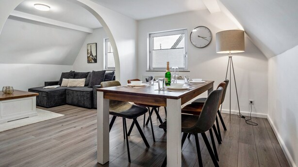 Un moderno loft con comedor, un sofá, una lámpara y un reloj en la pared.