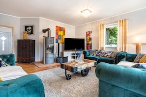 A living room with teal sofas, a wooden coffee table, a TV, and artwork on the walls. - Holiday Home 'Dreamliner' with Private Terrace, Wi-Fi and Air Conditioning (Sassnitz)