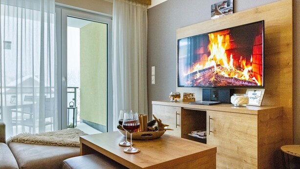 Una sala de estar moderna con una televisión de pantalla plana, una mesa de centro de madera y un sofá.