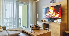 A modern living room with a flat-screen TV, a wooden coffee table, and a sofa.