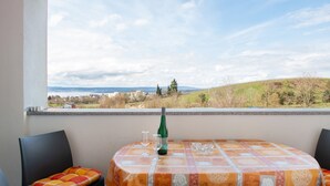 Uma varanda com mesa posta para dois, uma garrafa de vinho e vista para uma paisagem distante.