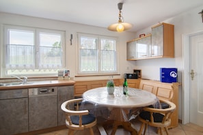 Une cuisine avec une table ronde, des chaises en bois, un évier, des placards et une fenêtre donnant sur un beau paysage.