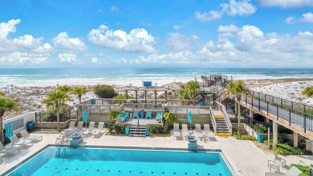 Un espace piscine avec des chaises longues et vue sur la plage.
