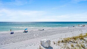 Une plage avec un filet de volley-ball, des gens qui se détendent et une tente au premier plan.