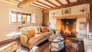 Una sala de estar acogedora con chimenea, un sofá, una mesa de centro y vistas al exterior a través de una ventana.