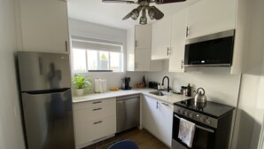 Una cocina compacta equipada con refrigerador, estufa, lavaplatos y ventilador de techo.