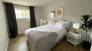 Un dormitorio con cama, mesitas de noche, una lámpara y una planta en maceta.