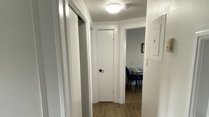 Un pasillo con paredes blancas y suelo de madera que conduce a un comedor con una mesa y sillas.
