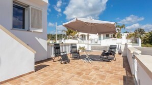 A rooftop patio with a large umbrella, outdoor seating, and a view of the surrounding landscape. - Gioia 1 by Interhome (Marina di Pescoluse)