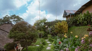 Un jardín con una estatua, un sendero y una casa con techo de tejas.