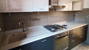 Een moderne keuken met een roestvrijstalen spoelbak, gasfornuis en donkere keukenkastjes.