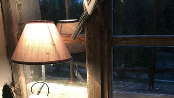 A lamp with a heart-shaped base on a table near a window with a wooden frame.