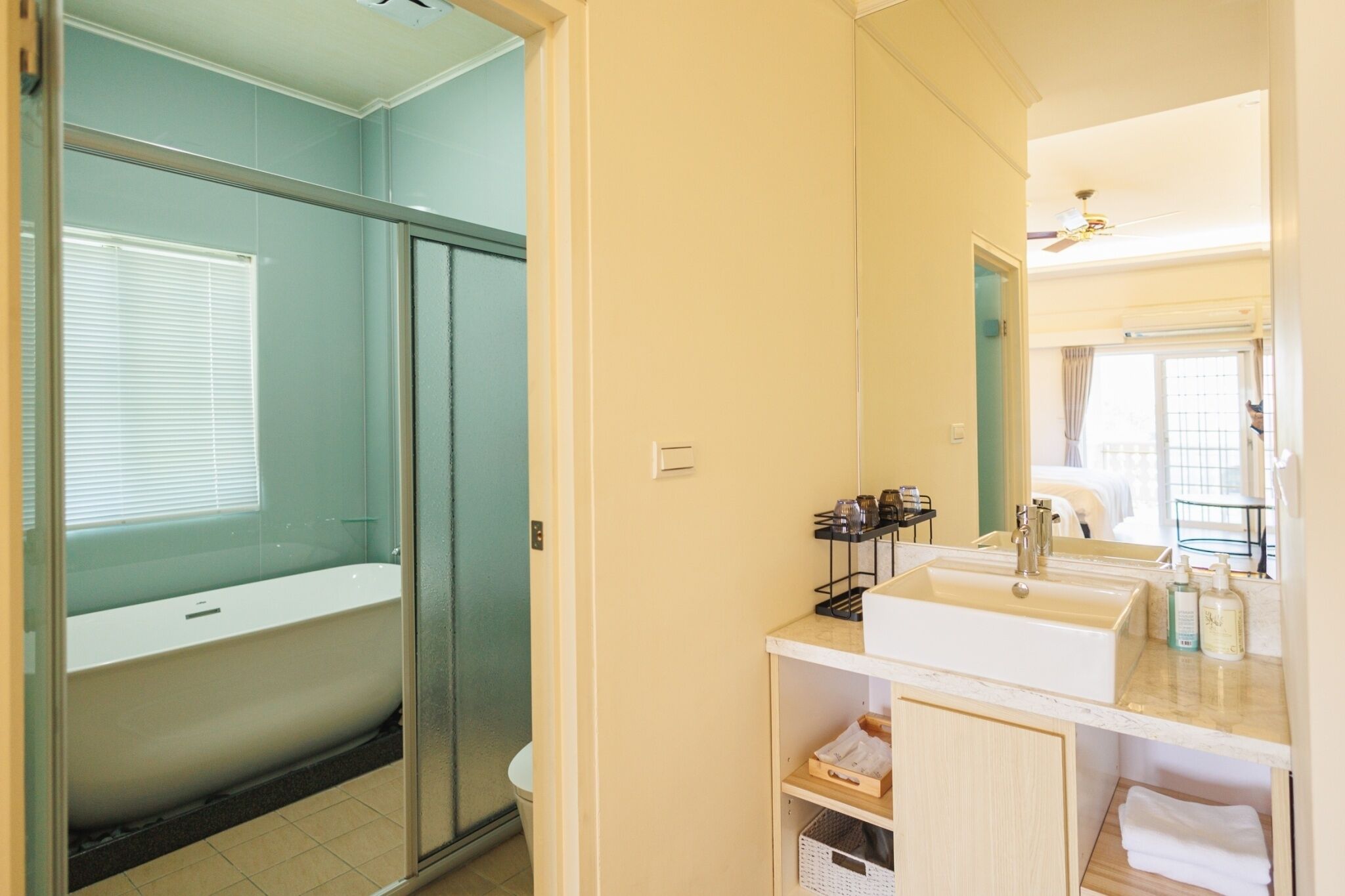 A bathroom with a glass-enclosed shower, a white bathtub, and a sink with toiletries.