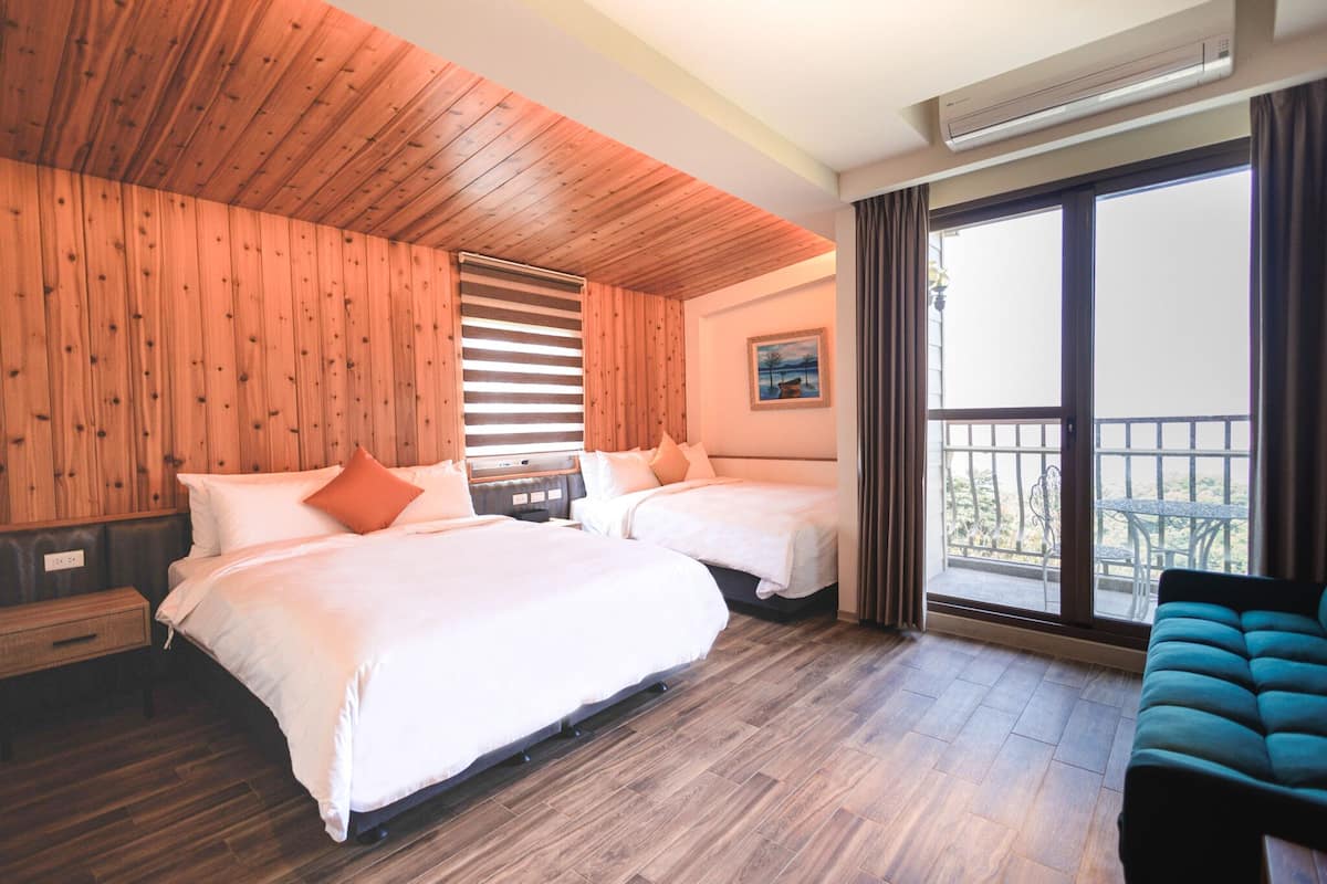 A hotel room with two beds, wooden ceiling, large window, and a balcony.