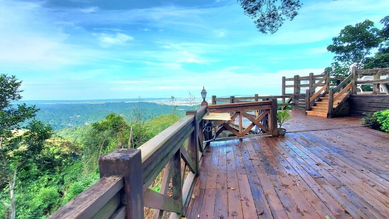 Une terrasse en bois dotée d’une rambarde, qui offre une vue sur un paysage montagneux.