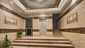 A modern lobby with marble walls, a staircase, and a door leading to another area. - DISCOVER Pyramids inn  (Giza)