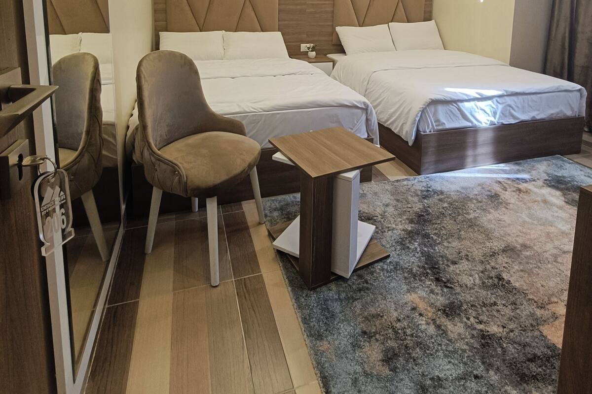 A hotel room with two beds, a desk, and a chair.
