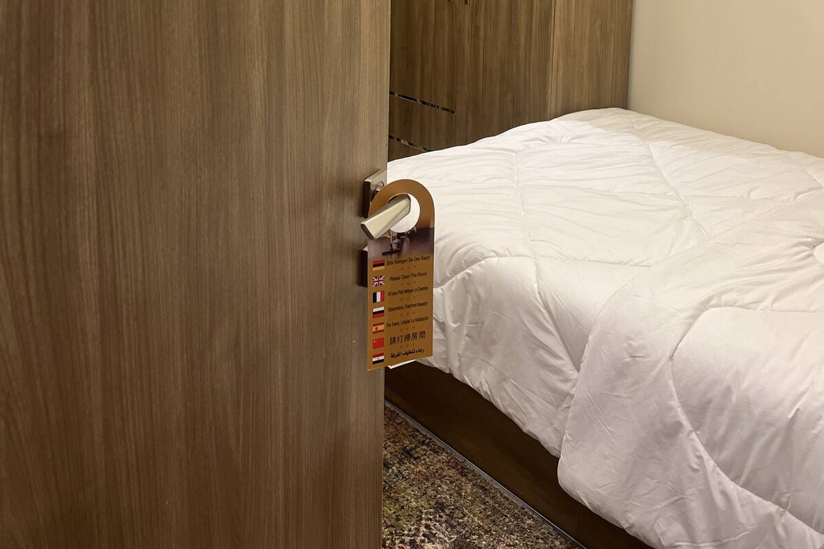 A hotel room with a wooden wardrobe, a bed with white bedding, and a sign indicating room number 201.