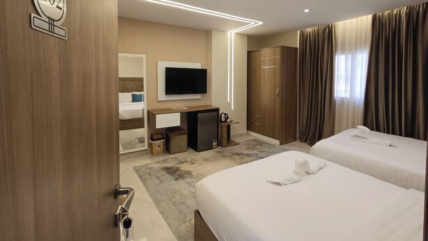 A modern hotel room with a bed, a desk, a television, and a wardrobe. - DISCOVER Pyramids inn  (Giza)