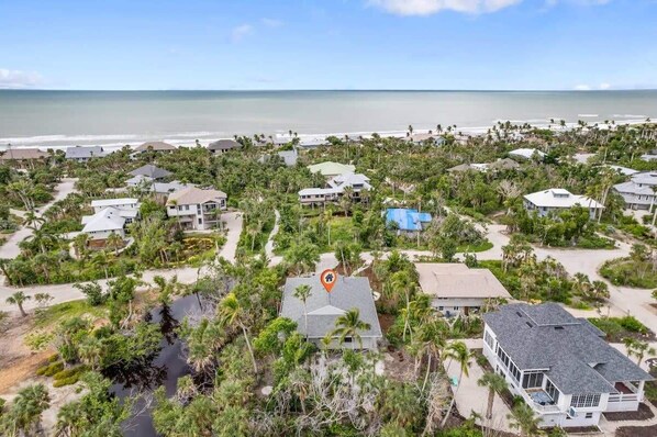 Un área residencial costera con casas rodeadas de vegetación y una playa al fondo.