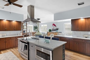 Una cocina moderna con armarios de madera, una isla central, electrodomésticos de acero inoxidable y un ventilador de techo.