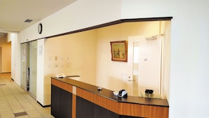 Una mesa de recepción con un teléfono, una lámpara de escritorio pequeña y un cuadro en la pared.