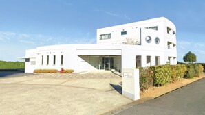 Un hotel moderno de color blanco con fachada curva, entrada cubierta y un letrero que indica que es un hotel.