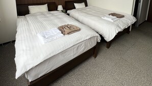 Habitación de hotel con dos camas, cabecero de madera, unidad de aire acondicionado y piso alfombrado.