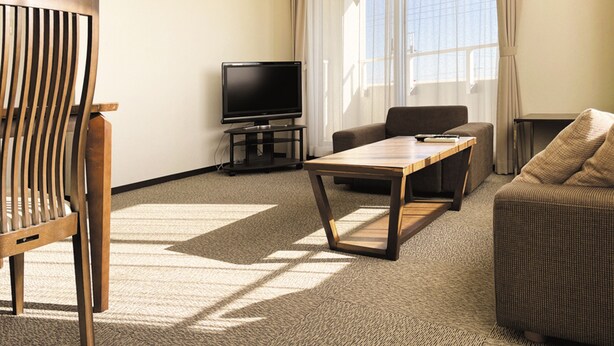 Una sala de estar moderna con una televisión de pantalla plana, una mesa de centro de madera, un sofá y una silla.