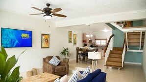 A spacious living area with a TV, comfortable seating, a dining area, and a kitchen in the background. - Captivating 2-Bed Town-House in Kingston (Kingston)