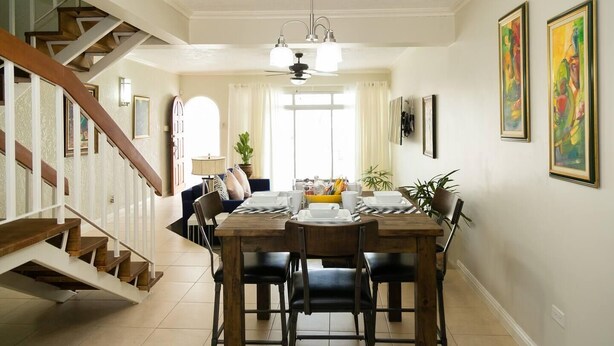 A dining area with a wooden table, chairs, and a staircase. - Captivating 2-Bed Town-House in Kingston (Kingston)