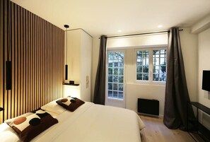 Un dormitorio moderno con cama, ventana con cortinas, televisor montado en la pared y diseño de panel de madera.