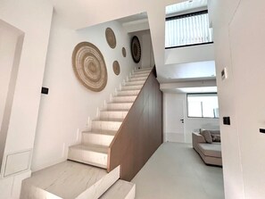 A modern interior with a staircase leading to a loft area, featuring minimalist decor and a neutral color palette.