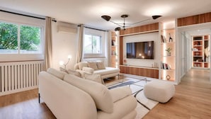 A modern living room with a sofa set, a TV, and built-in shelving. - Magnificent - 3 bedrooms - near Tour Eiffel (Paris)
