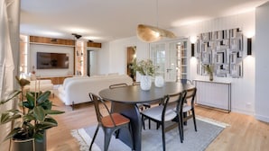 A modern living room with a round dining table, comfortable seating, a large TV, and decorative wall panels. - Magnificent - 3 bedrooms - near Tour Eiffel (Paris)