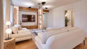 A modern living room with a large flat-screen TV, a sofa set, a coffee table, and a decorative lamp. - Magnificent - 3 bedrooms - near Tour Eiffel (Paris)